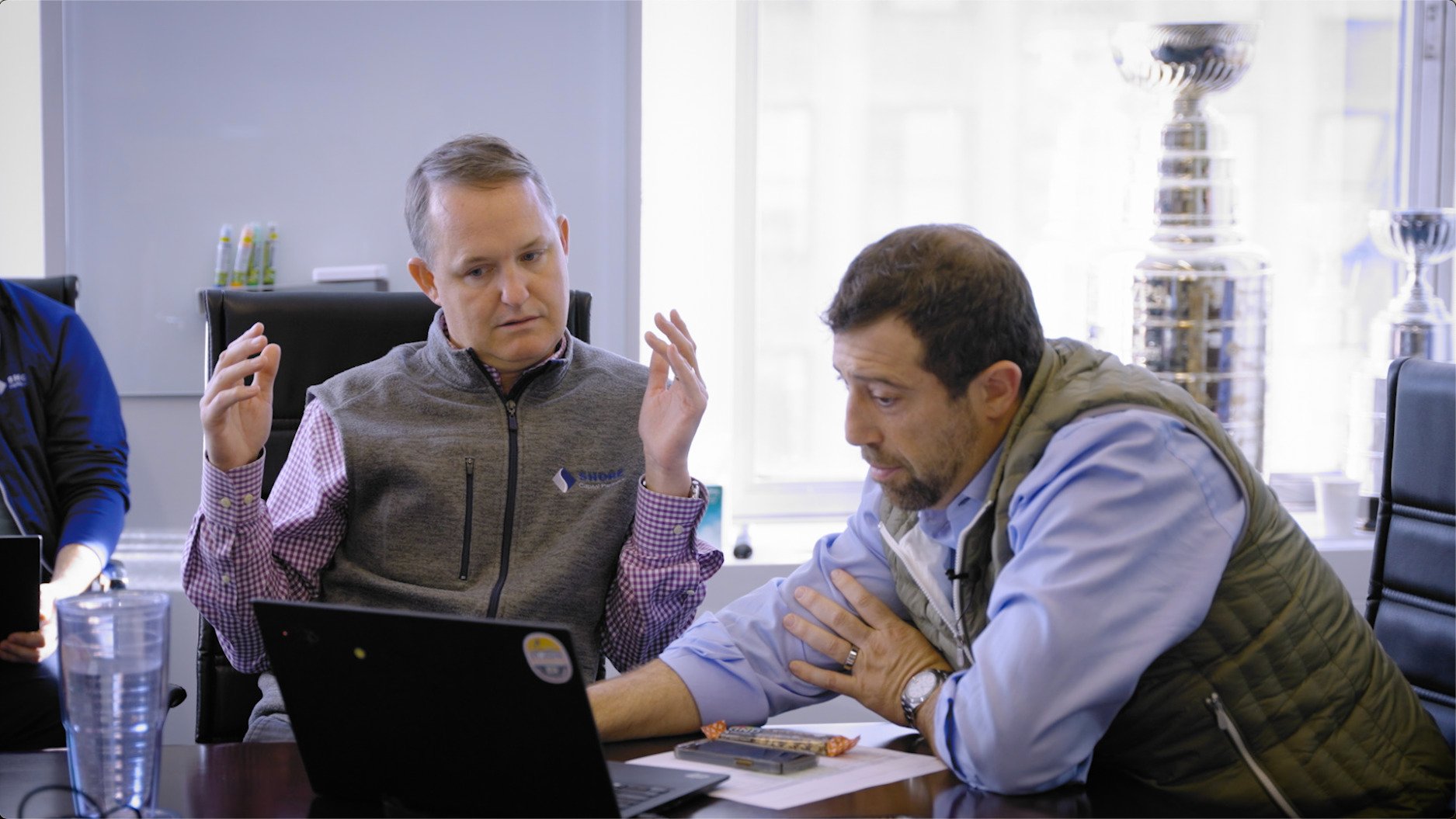Justin Ishbia and John Hennegan working together over laptop at conference room table
